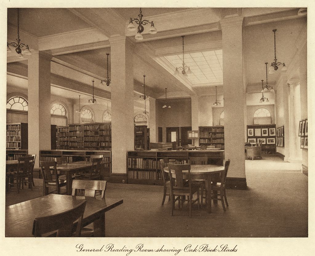 A historic library reading room lined with oak book stacks